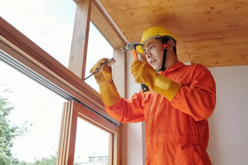 worker removing old wooden window frame